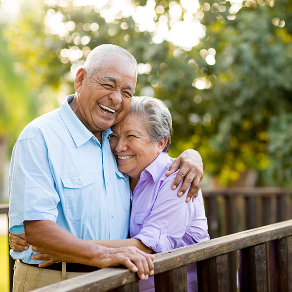 A senior couple is laughing and hugging while posing for the camera