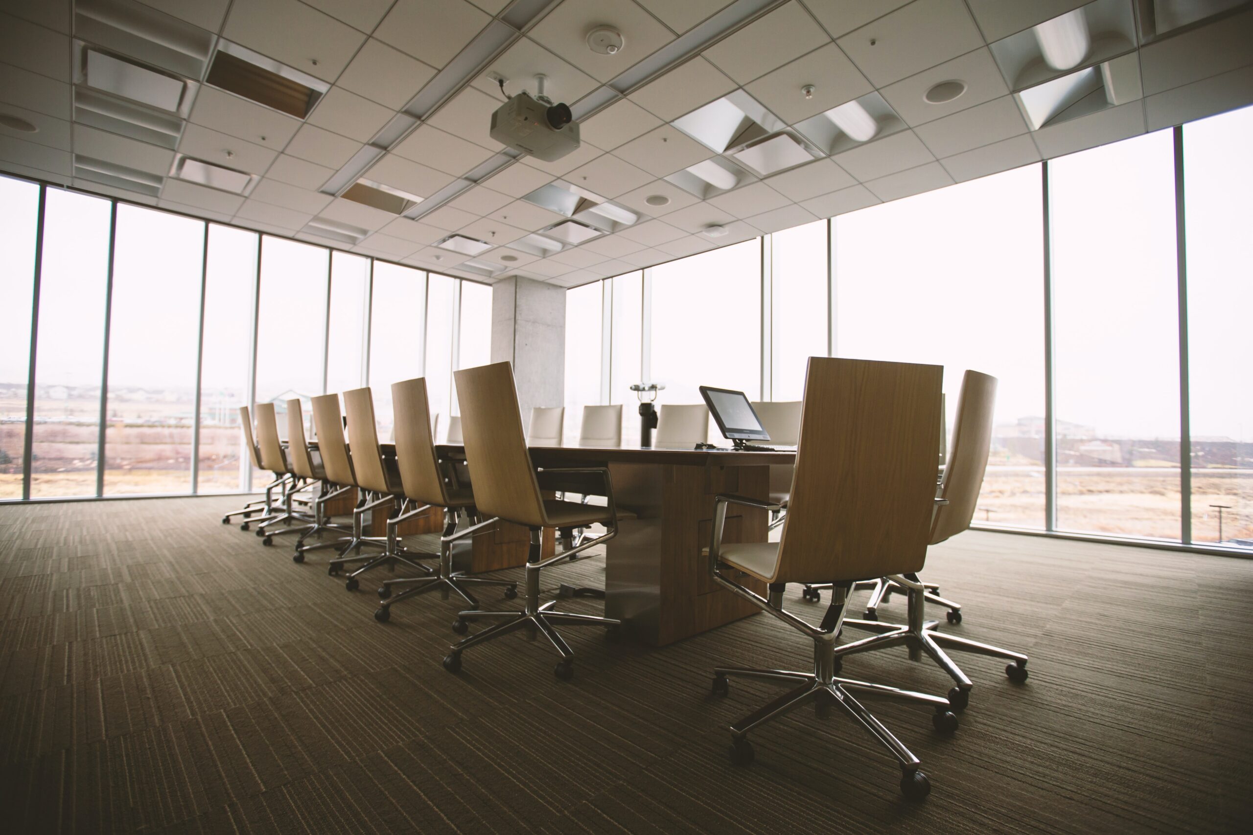 An empty business board room with office chairs and a big table.