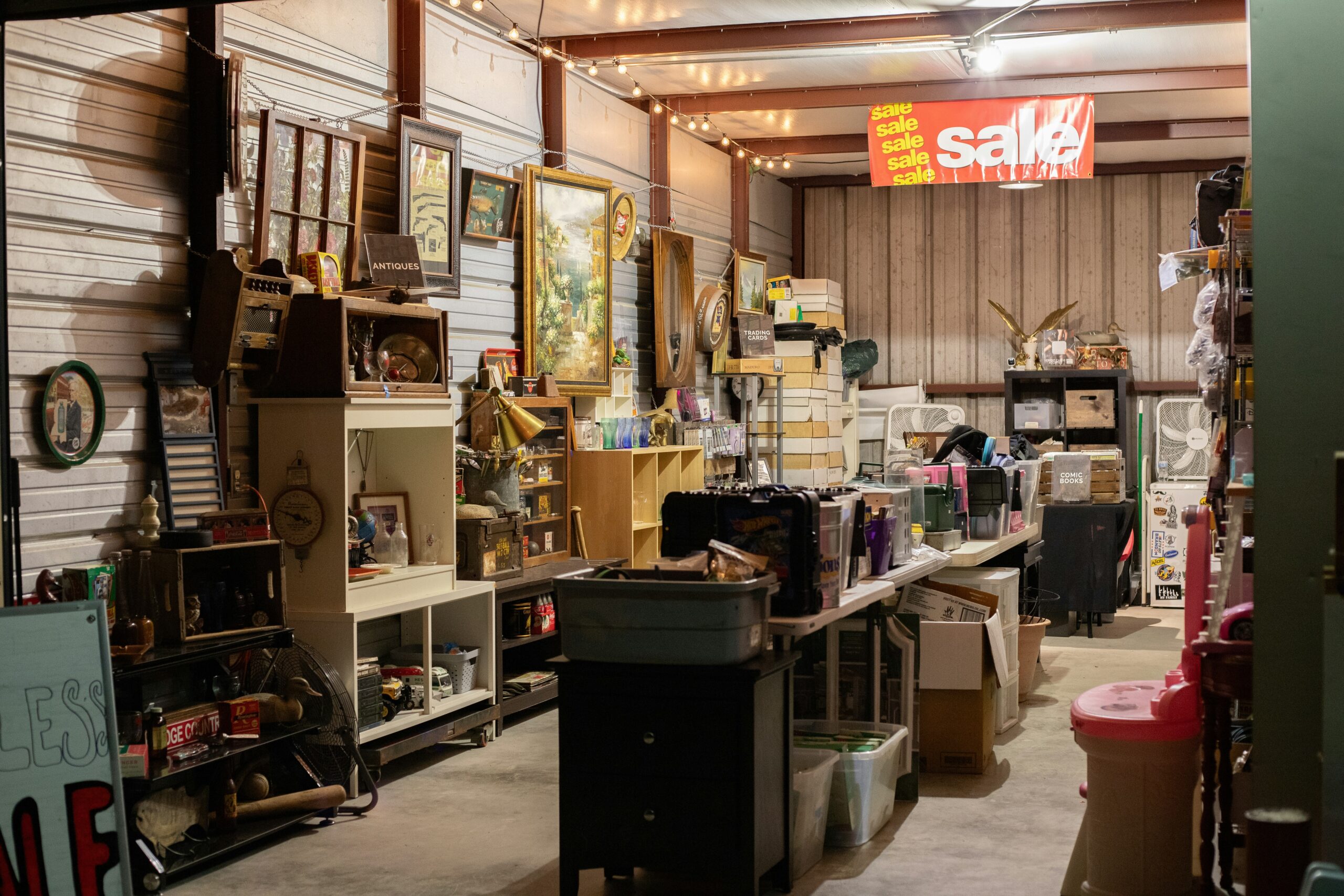 The picture displays an estate sale with a room full of contents and a for sale sign.